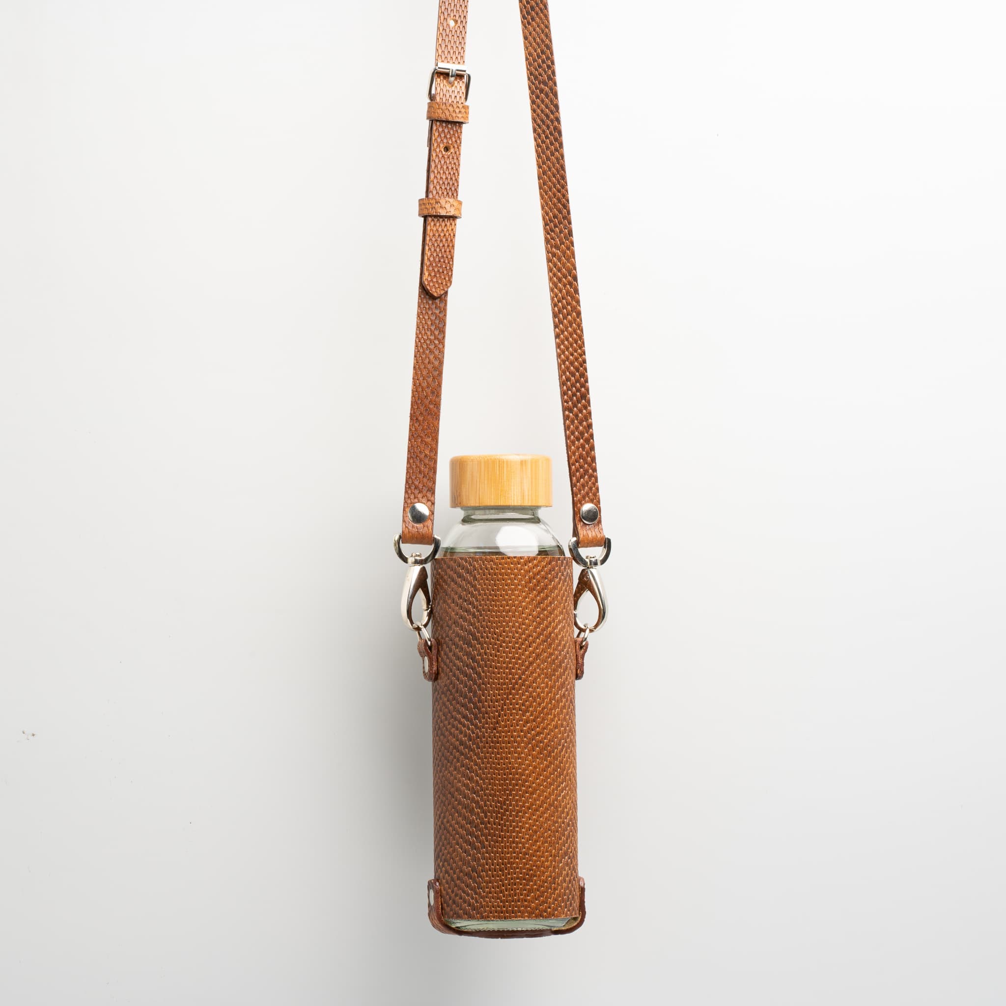 Leather water bottle holder with strap and glass bottle by Geometric Goods