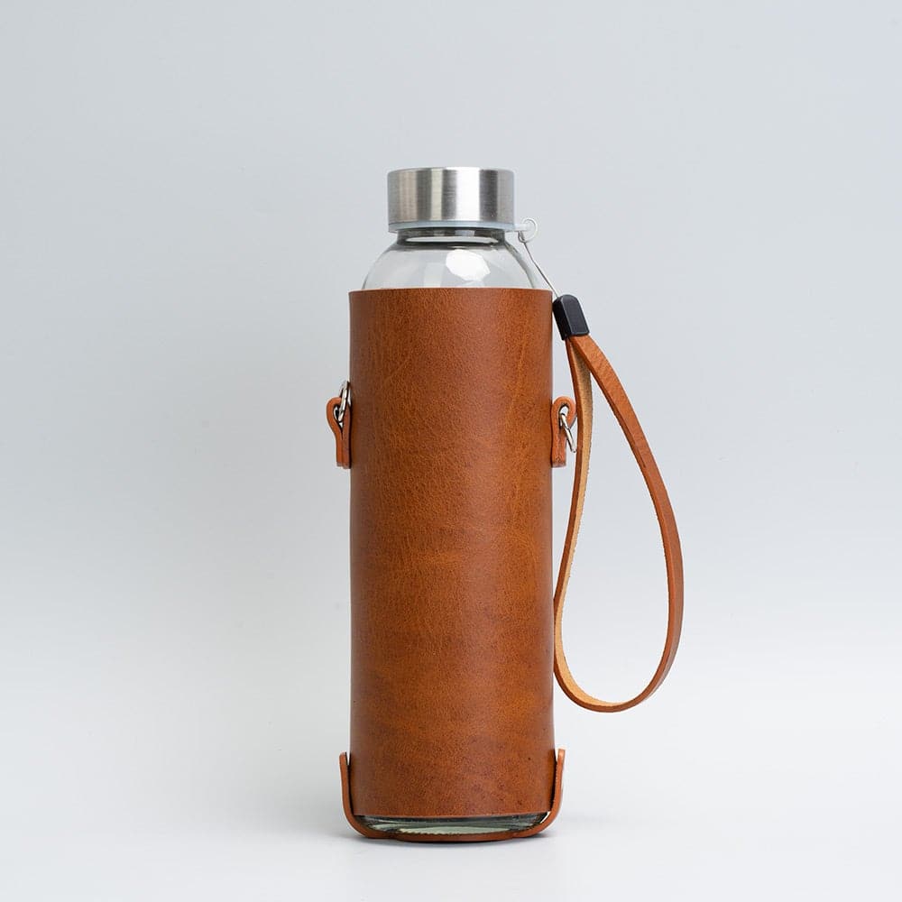 Leather water bottle holder with strap and glass bottle by Geometric Goods
